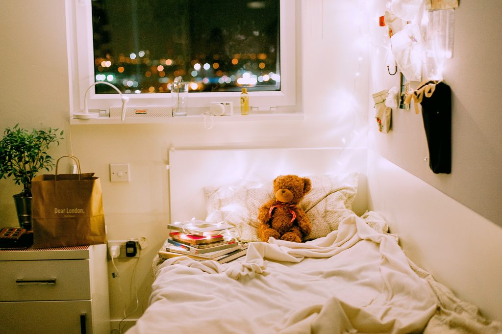 teddy bear in child's bed with white christmas lights